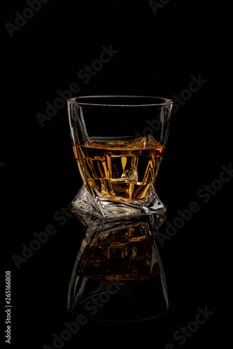 The glass of whisky on black background. Side view. Blank space.
