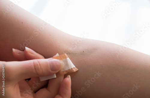 Obraz na płótnie woman removing adhesive plaster off injury after blood test injection w salonie