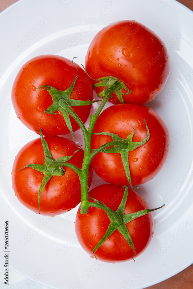 tomatoes on a branch in a white plate tomatoes on a branch in a white plate