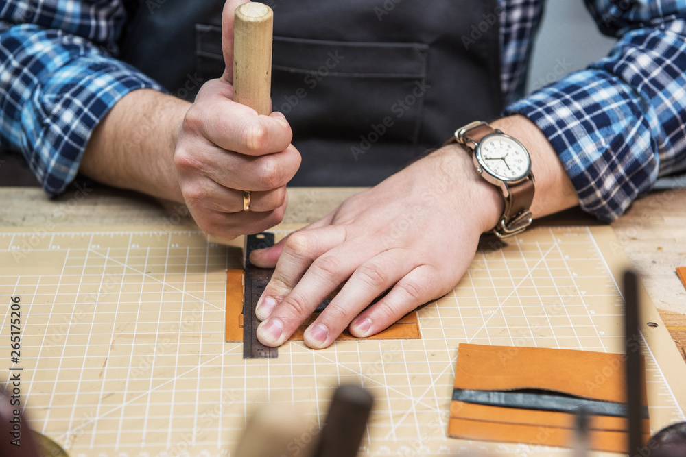 Obraz premium Man working with leather textile at a workshop.