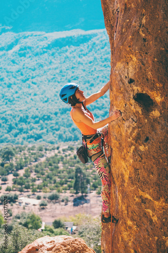 A girl in a helmet climbs a rock.