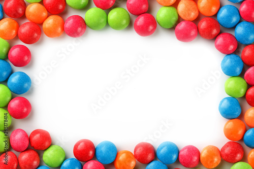 Frame of multi-colored candies close up. Rainbow colored dragee multicolored glaze on a white background