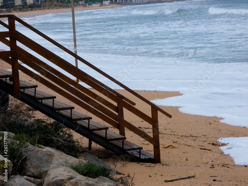 Escalera en la arena de la playa, esperando que el temporal amaine