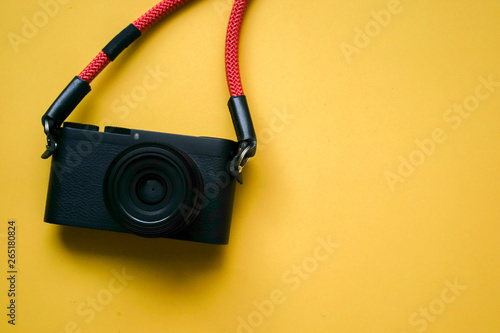 close up top view of black camera with red strap on yellow background