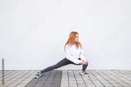 Attractive sports girl warm up before training on the background of a white wall. Fitness girl is stretched on a white background. Sports concept.