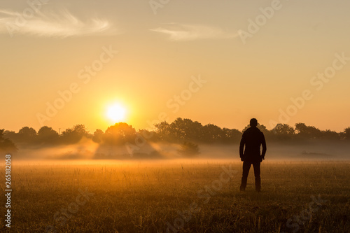 Silhouette of man in field at sunrise