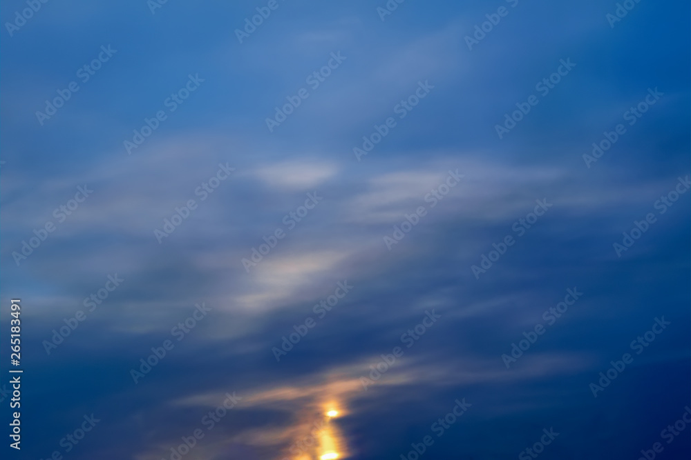 Blue sky with gold clouds - dramatic sunset, beautiful natural background. Setting sun illuminates the clouds.