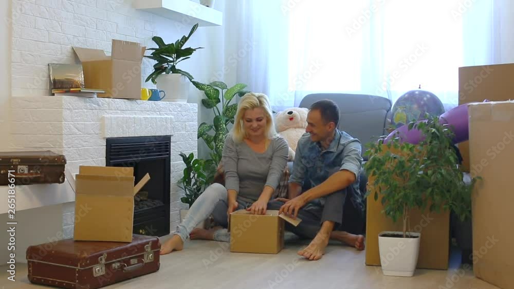 Happy excited family with two unpacking boxes moving into new home concept, on sofa in living room after relocation Happy excited family with two unpacking boxes moving into new home concept, on sofa in living room after relocation