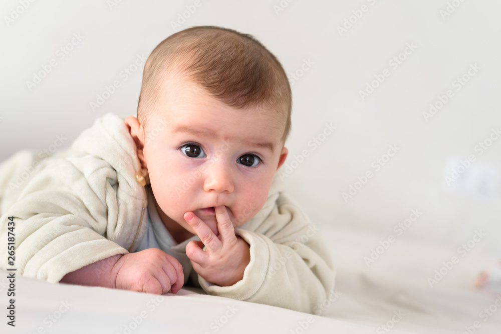 Portrait of an adorable smiling baby biting her own fingers putting her fist in her mouth. Portrait of an adorable smiling baby biting her own fingers putting her fist in her mouth.