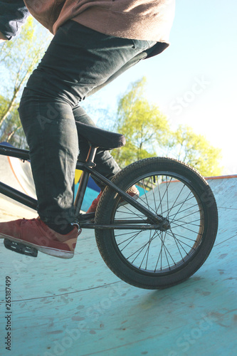 Close up of a BMX bike with a young extremals cyclist on a special ramp for tricks. Hobbies of modern youth. photo