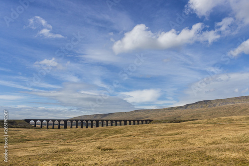 Famous Ribbleshead Viaduct in Yorkshire dales, blue sky and hills.