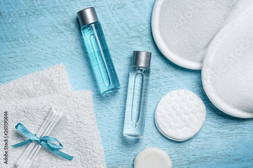 Disposable slippers and towels with shower gel and shampoo on a blue wooden background