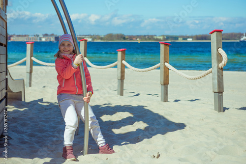 Adorable little girl playing at playground on a beach photo