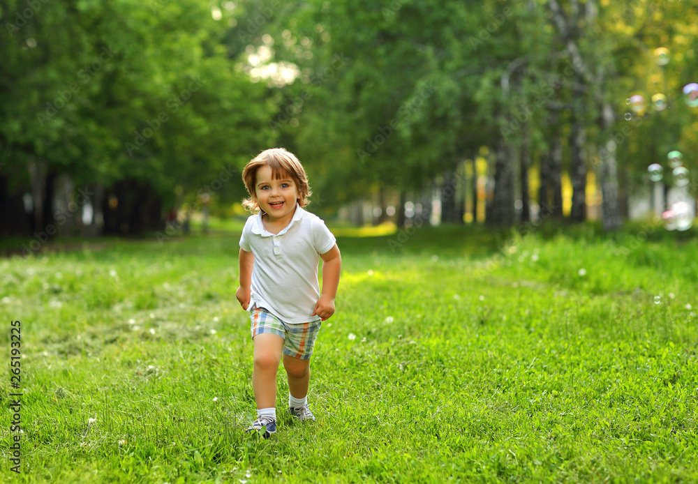 Beautiful 2 year old boy playing in the summer outside in the greenery with soap bubbles Beautiful 2 year old boy playing in the summer outside in the greenery with soap bubbles