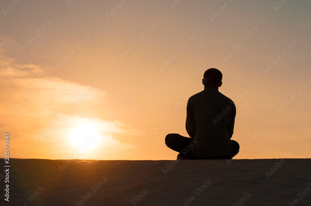 man in the lotus position at sunset