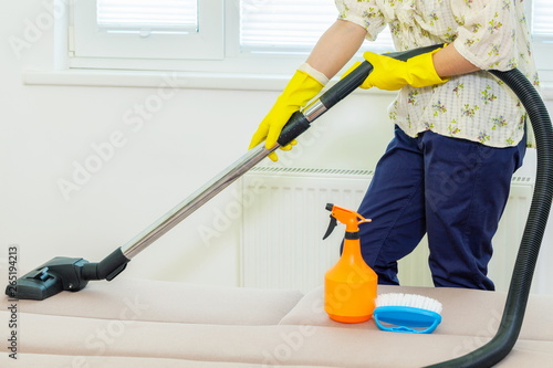 Woman cleaning a couch with a vacuum cleaner