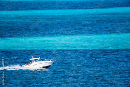 Bote deportivo navegando por el mar caribe con personas disfrutando de un día soleado en el mar caribe de Cancin, Mexico, contraste de colores azul turquesa photo