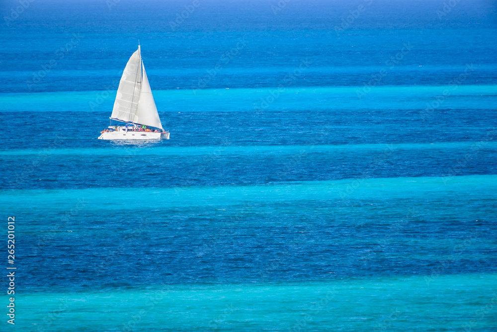 Obraz premium Velero de dos velas navegando en el mar caribe con contraste colores azul turquesa, Cancun, Mexico