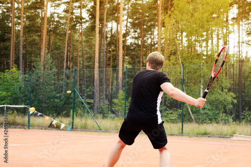 Male tennis player in action on the court in the evening sunset © Romo Lomo