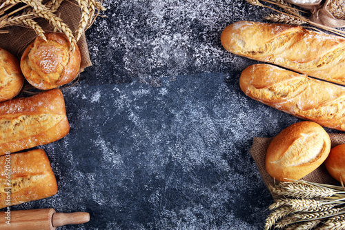 Assortment of baked bread and bread rolls on rustic grey bakery table background