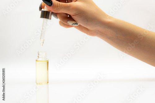 Cosmetic pipette with drops of cosmetic oil close-up on a white background