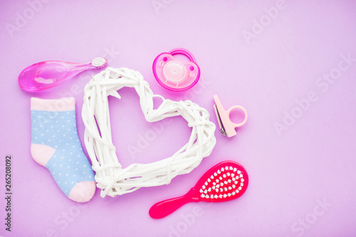 Newborn baby story. Strow heart and children's toys, scissors, baby bottle, nipple, hairbrush on violet background © 976photo