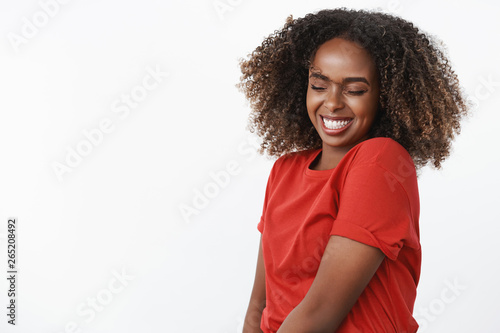 Dance like no one watching. Portrait of carefree and silly happy beautiful and sincere afrian-american young woman waving head and jumping with closed eyes and broad joyful smile over white wall photo
