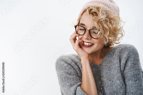 Close-up shot of sensual and tender flirty hipster girl in winter beanie and sweater close eyes tilting head and smiling coquettish touching cheek tender and gentle, recalling nice warm memories