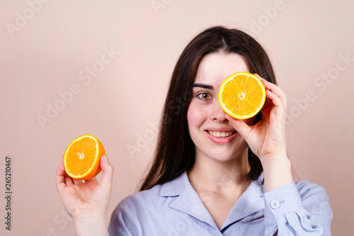 Healthy food, vitamin C, body care, cosmetology. Happy cheerful funny girl holding halves of orange near face