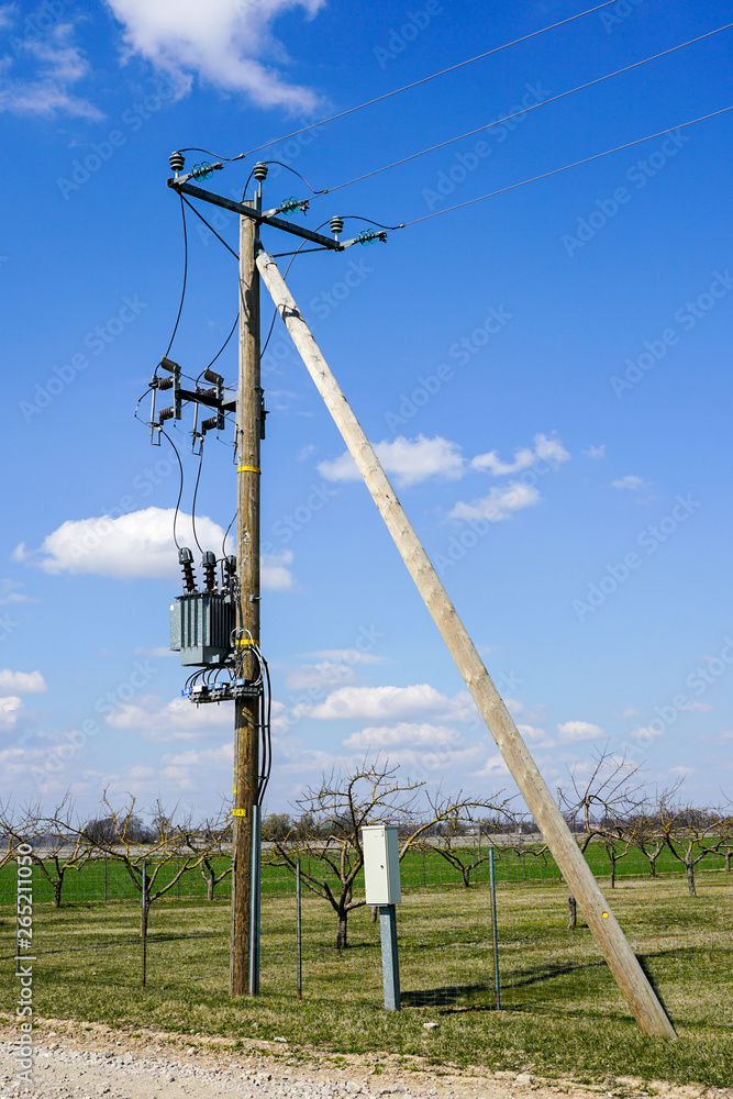 wooden power line pole with electric transformer in rural area