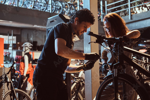 Young master and his attractive apprentice are fixing customer's bicycle at workshop.
