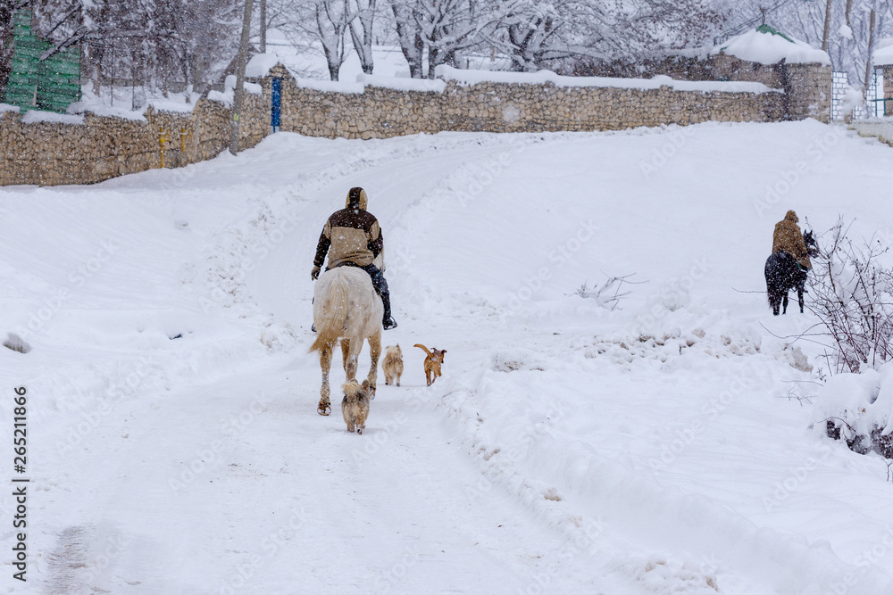 Farmer riding a horse in the winter.