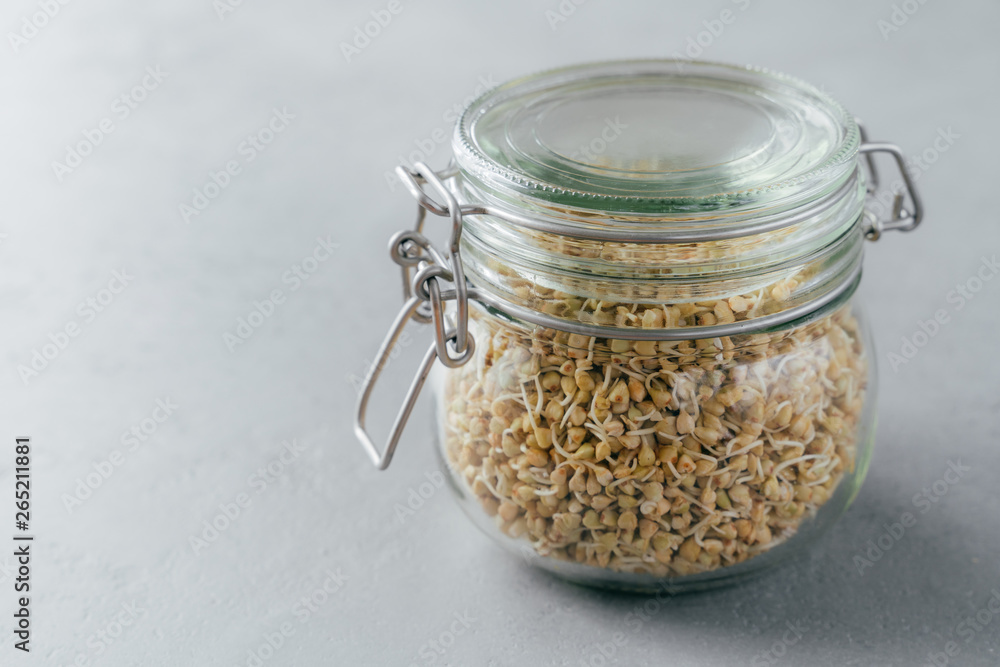 Glass jar of buckwheat sprouts against grey background. Vegetarian dish concept. Organic nutrition. Eco eating concept. Healthy food Glass jar of buckwheat sprouts against grey background. Vegetarian dish concept. Organic nutrition. Eco eating concept. Healthy food