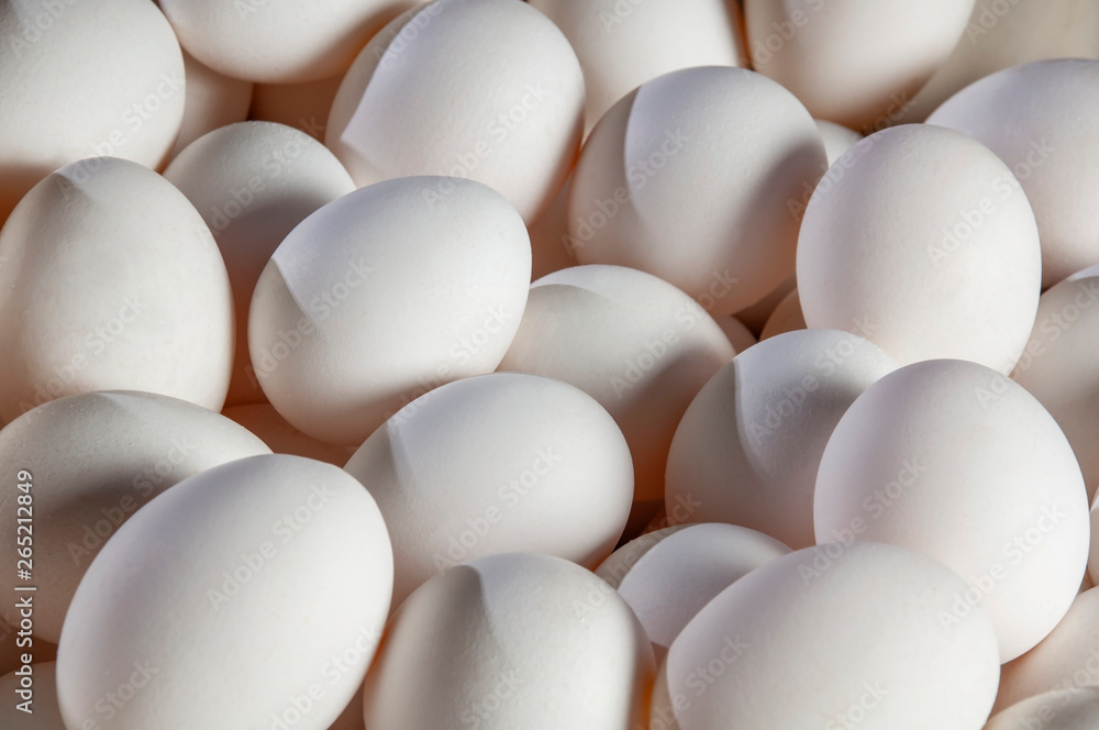 Pile of white chicken eggs. Great light and shadows casted over an elliptical group of eggs Pile of white chicken eggs. Great light and shadows casted over an elliptical group of eggs