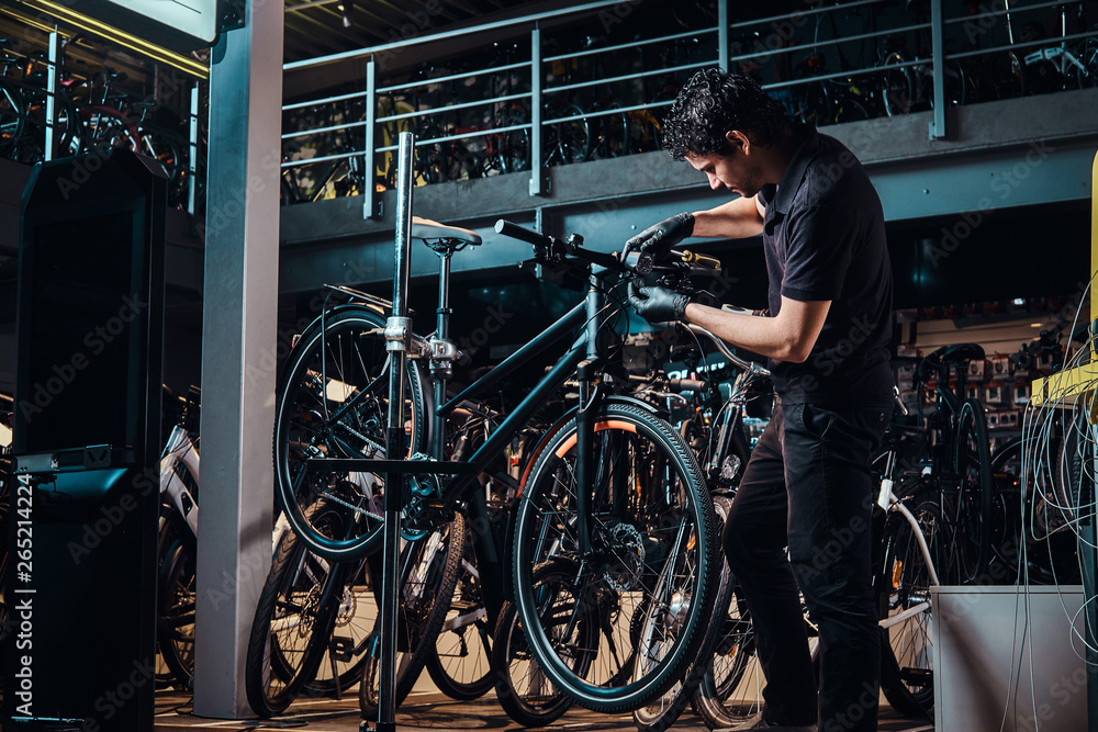 Expirienced young master is repairing customer's bicycle at workplace. Expirienced young master is repairing customer's bicycle at workplace.