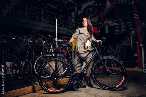 Diligent attractive woman is trying fixed bicycle at busy workshop.