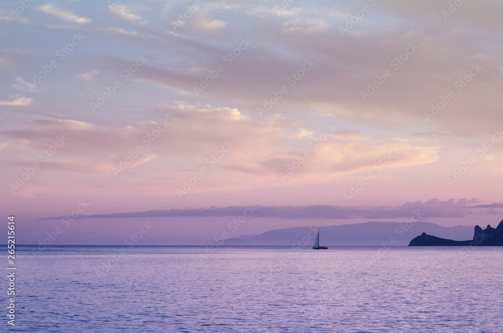 Beautiful pastel toned sunset or sunrise view from the seaside. Yacht on the calm sea surface.