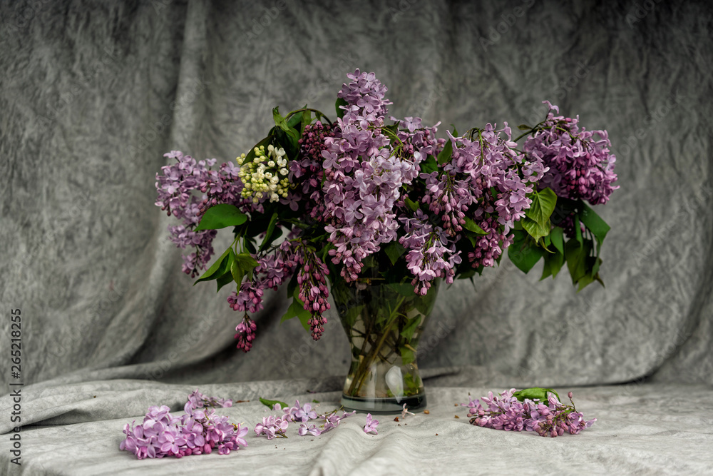 Bouquet of lilac in a glass vase. A bouquet of lilac on a white tablecloth table. Bouquet of lilac in a glass vase. A bouquet of lilac on a white tablecloth table.