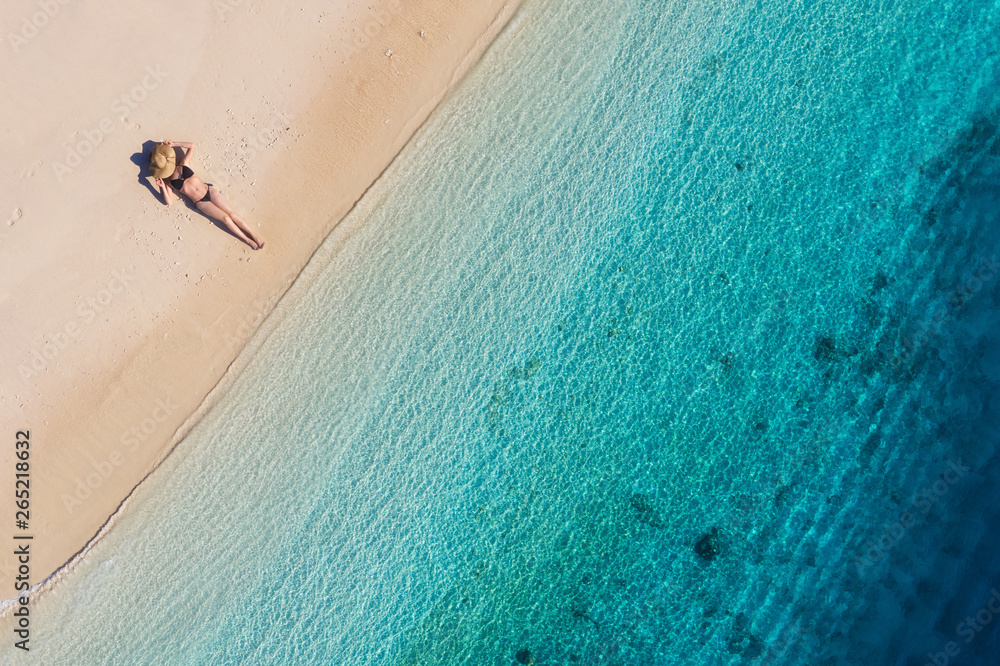 Obraz premium Aerial view of a girl on the beach on Bali, Indonesia. Vacation and adventure. Beach and turquoise water. Top view from drone at beach, azure sea and relax girl. Travel and relax - image