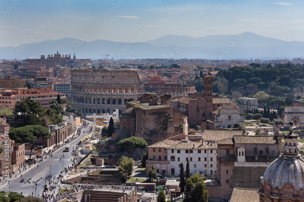Rome, Italy - march, 2019: View to rooftops of Rome skyline from the Monument of Vittorio Emanuele II at Piazza Venezia. Rome Forum with ruins of historical buildings. Colosseum in the background