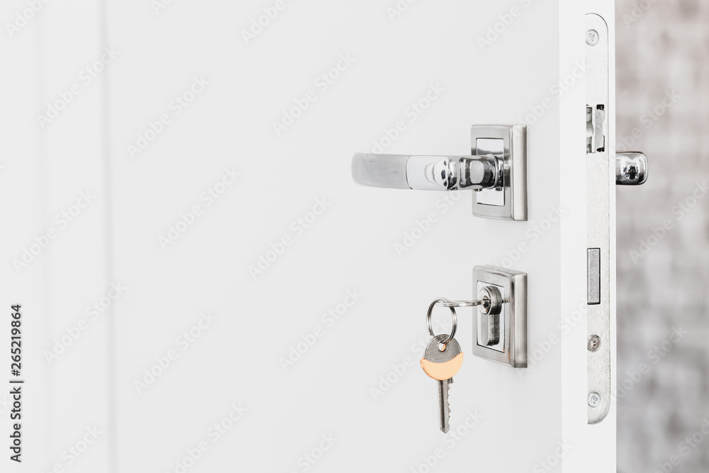 Open white door at home. Handle key close up. Open white door at home. Handle key close up.