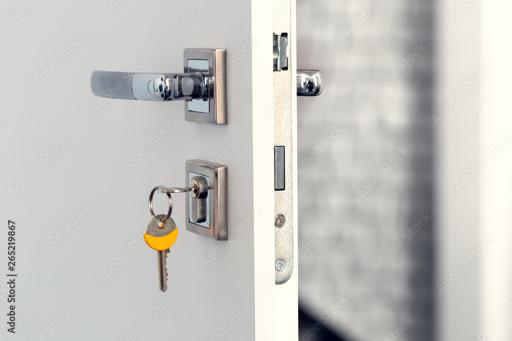 Naklejka premium Open white door at home. Handle key close up.