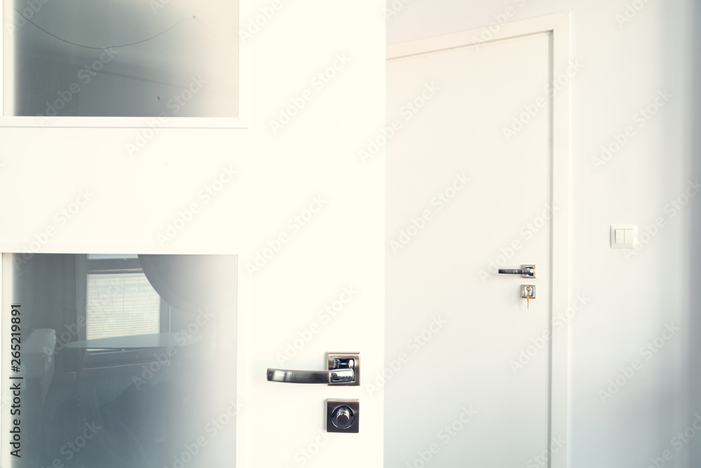 Open white door at home. Handle key close up. Open white door at home. Handle key close up.