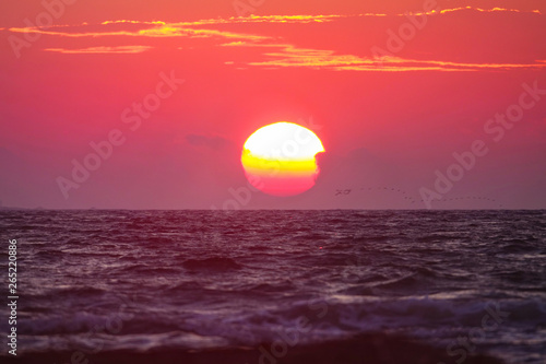 Fototapeta Naklejka Na Ścianę i Meble -  Waves crashing against each other as the sun sets behind the sea in Dalmatia.