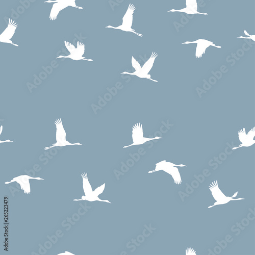Seamless pattern with a flock of white cranes on a blue background. Vector.