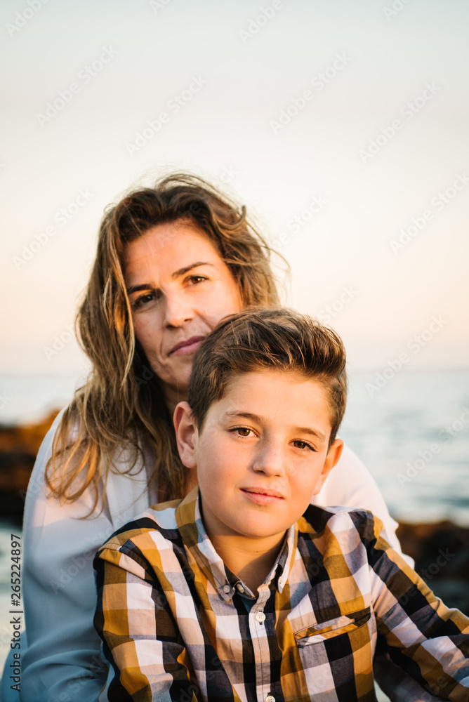 Middle aged woman with her son at sea shore smiling and hugging each other Middle aged woman with her son at sea shore smiling and hugging each other