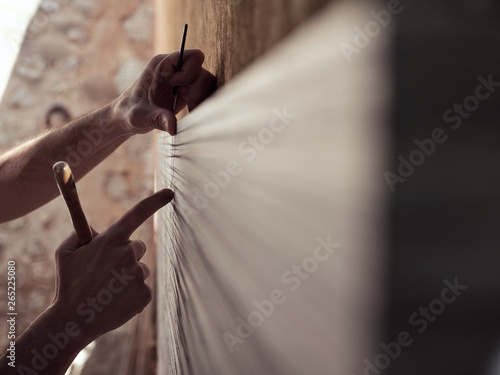 Hands of anonymous male artist with painting tools touching canvas while working in workshop photo