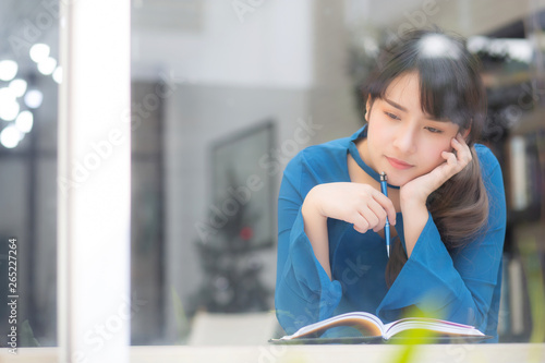 Beautiful portrait young asian woman writer thinking idea and writing on notebook or diary with happy, lifestyle of asian girl is student, female planning working, education and business concept.