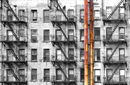 Canvas Print Black and white apartment building with colorful old rusted metal pipes in New Y