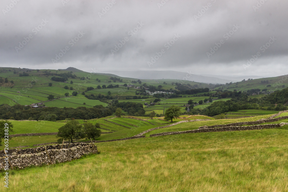 Yorkshire landscape with green fields, dry stone walls and dark clouds